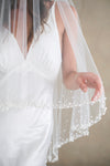 Model wears a wedding veil, drop veil with pearls and sequins