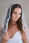 Model wears a lace wedding veil, one tier veil with lace edge.