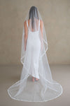 Model wears a lace wedding veil, one tier veil with lace edge.