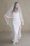 Model wears a lace wedding veil, drop veil with lace trim.