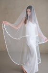 Model wears a lace wedding veil, drop veil with lace trim.