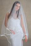 Model wears a lace wedding veil, drop veil with lace trim.