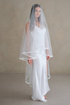 Model wears a lace wedding veil, drop veil with lace trim.