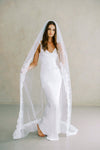 Model wears a lace wedding veil, one tier veil with partial lace trim.