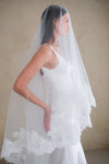 Model wears a lace wedding veil, drop veil with lace trim.