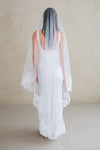 Model wears a lace wedding veil, drop veil with lace trim.