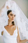 Model wears a lace wedding veil, drop veil with lace trim.