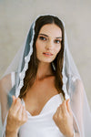 Model wears a lace wedding veil, one tier veil with lace edge.