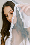 Model wears a lace wedding veil, one tier veil with lace edge.